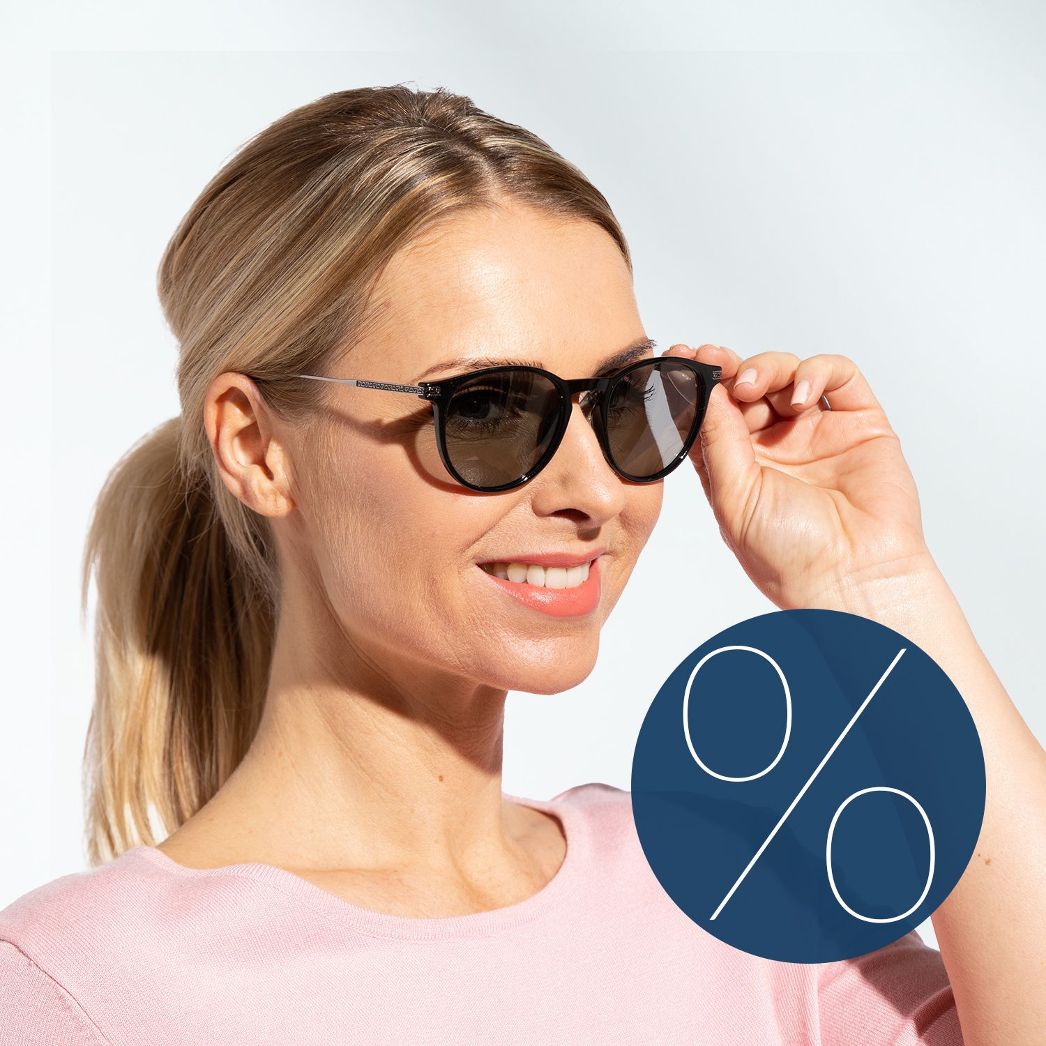 Sonnenbrillen-Sale Frau mit hellblondem Pferdeschwanz, rosa Oberteil und Sonnenbrille neben einem blauen Kreis mit großem, weißen Prozentzeichen